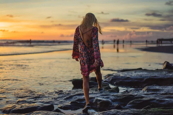 gün batımında sahilde insanlar. Kız batan güneşin fonunda atlıyor.