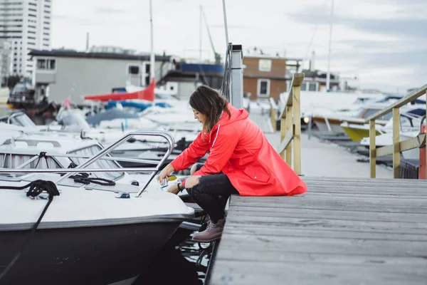Beautiful young woman in a red cloak in the yacht port. Stockholm, Sweden