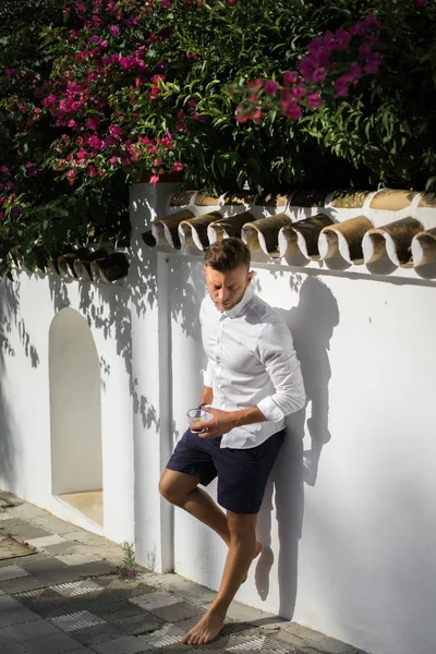Beyaz gömlekli adam yazın açık havada kahve içer.