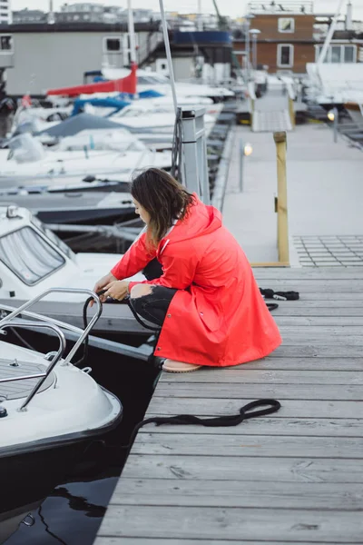 Beautiful young woman in a red cloak in the yacht port. Stockholm, Sweden