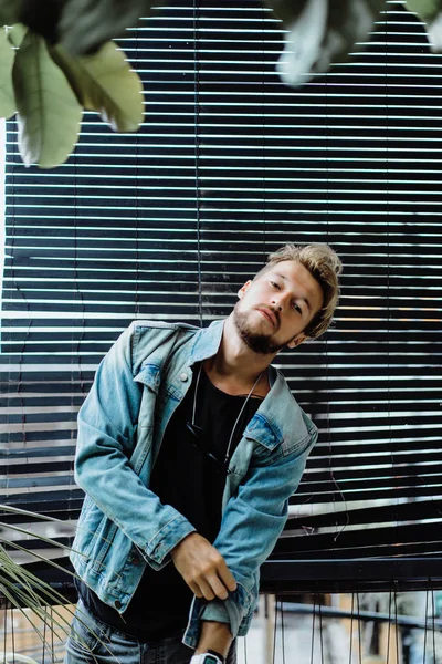 tropikal bir yerde, palmiye ağaçları ve yeşil, güneş gözlüklü bir arka plan üzerinde poz genç çekici adam