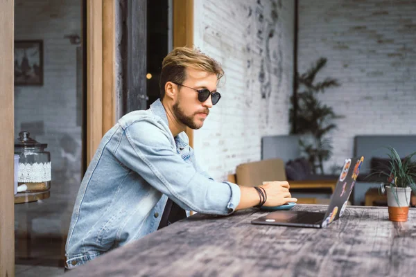 genç çekici iş adamı için bir dizüstü bilgisayar, bir kafe eserlerinde kahve içiyor.