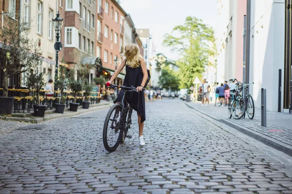 Şehirde bisiklet süren genç bir kadın.