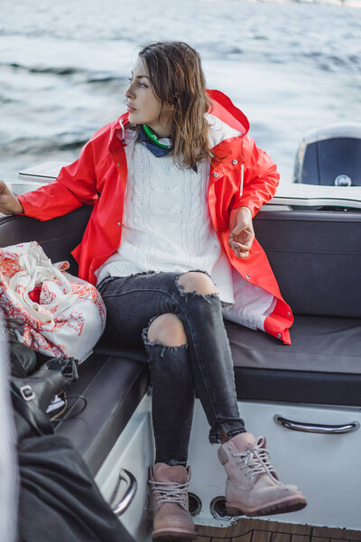 beautiful young woman in a red raincoat rides a private yacht. Stockholm, Sweden