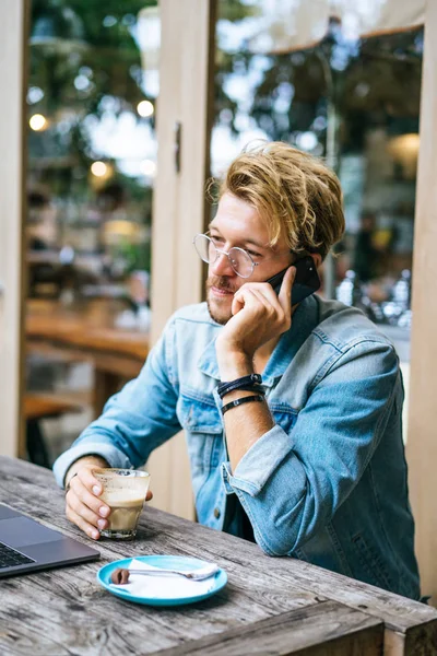 genç çekici iş adamı için bir dizüstü bilgisayar, bir kafe eserlerinde kahve içiyor.