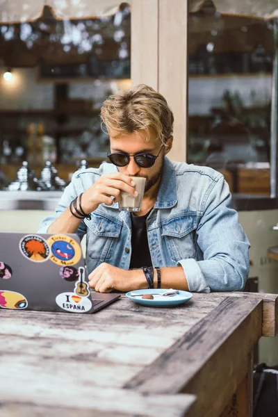 genç çekici iş adamı için bir dizüstü bilgisayar, bir kafe eserlerinde kahve içiyor.