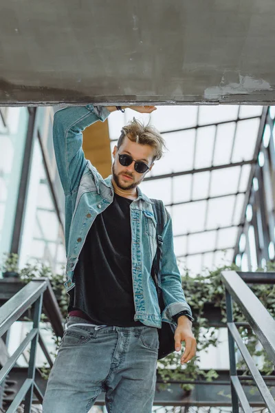 tropikal bir yerde, palmiye ağaçları ve yeşil, güneş gözlüklü bir arka plan üzerinde poz genç çekici adam