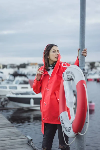 Beautiful young woman in a red cloak in the yacht port. Stockholm, Sweden