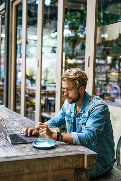 genç çekici iş adamı için bir dizüstü bilgisayar, bir kafe eserlerinde kahve içiyor.