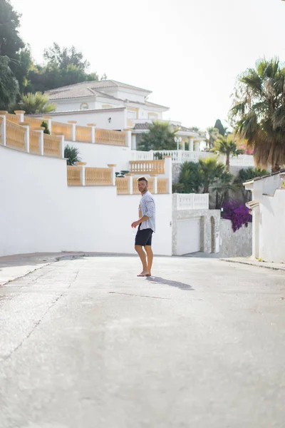 çizgili gömlekli, hasır şapka giyen bir adam, küçük bir İspanyol kasabasının sokaklarında yürüyor..