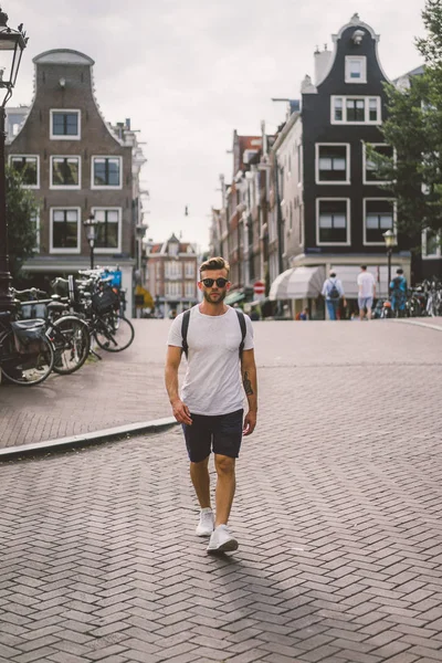 Bir insan bir sırt çantası ile Amsterdam sokaklarında yürüyor.