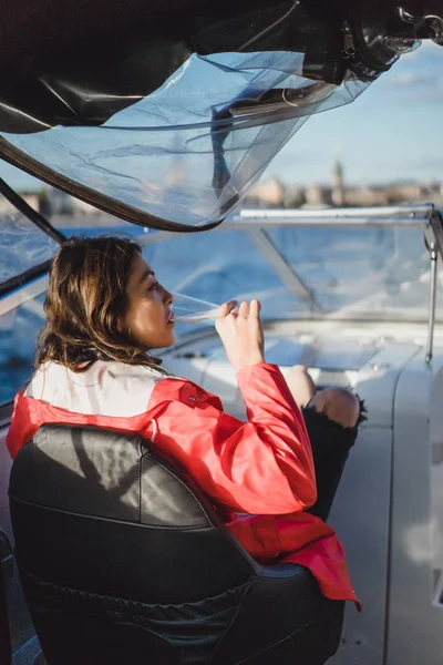 beautiful young woman in a red cloak drinking champagne on a yacht.