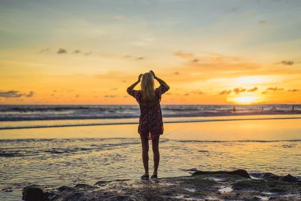 gün batımında sahilde insanlar. Kız batan güneşin fonunda atlıyor.