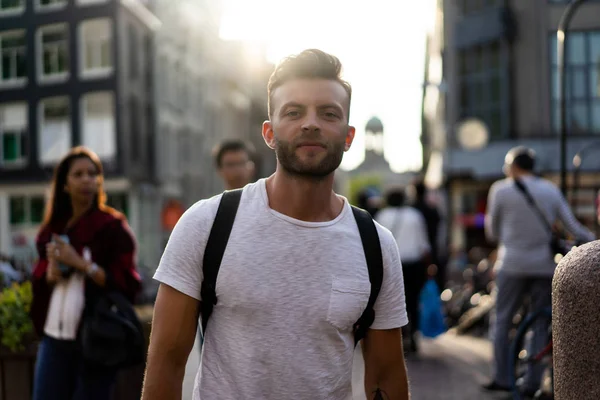 Bir insan bir sırt çantası ile Amsterdam sokaklarında yürüyor.