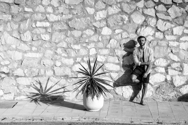 çizgili gömlekli, hasır şapka giyen bir adam, küçük bir İspanyol kasabasının sokaklarında yürüyor..