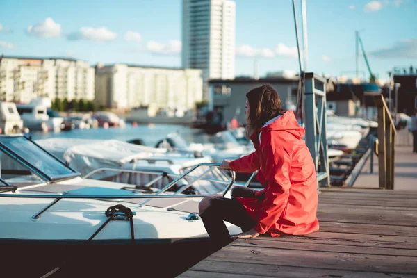 Beautiful young woman in a red cloak in the yacht port. Stockholm, Sweden