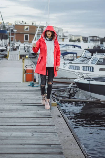 Beautiful young woman in a red cloak in the yacht port. Stockholm, Sweden