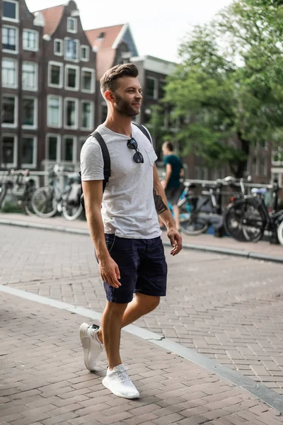 Bir insan bir sırt çantası ile Amsterdam sokaklarında yürüyor.