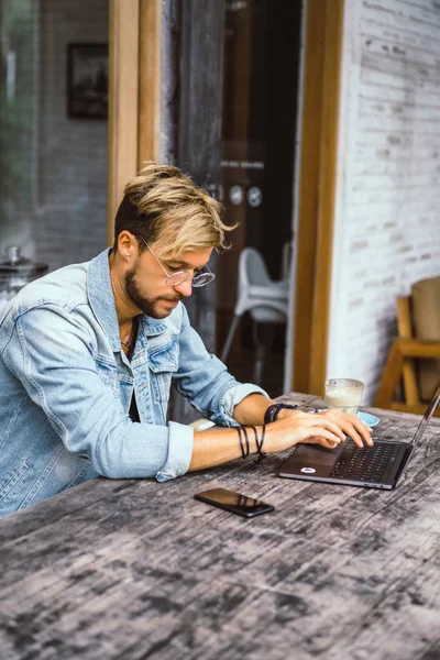 genç çekici iş adamı için bir dizüstü bilgisayar, bir kafe eserlerinde kahve içiyor.