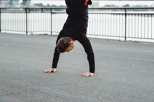 Yakışıklı atletik genç adam dışarıda egzersiz yapıyor.