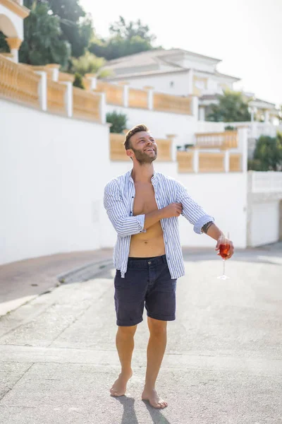 çizgili gömlekli, hasır şapka giyen bir adam, küçük bir İspanyol kasabasının sokaklarında yürüyor..