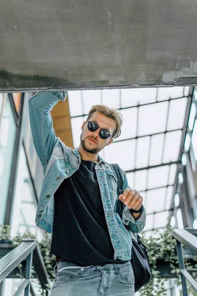 tropikal bir yerde, palmiye ağaçları ve yeşil, güneş gözlüklü bir arka plan üzerinde poz genç çekici adam