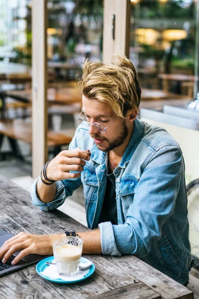 genç çekici iş adamı için bir dizüstü bilgisayar, bir kafe eserlerinde kahve içiyor.