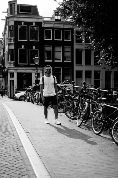 Bir insan bir sırt çantası ile Amsterdam sokaklarında yürüyor.