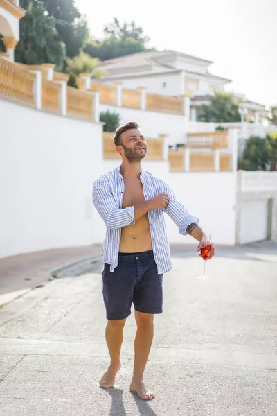 çizgili gömlekli, hasır şapka giyen bir adam, küçük bir İspanyol kasabasının sokaklarında yürüyor..