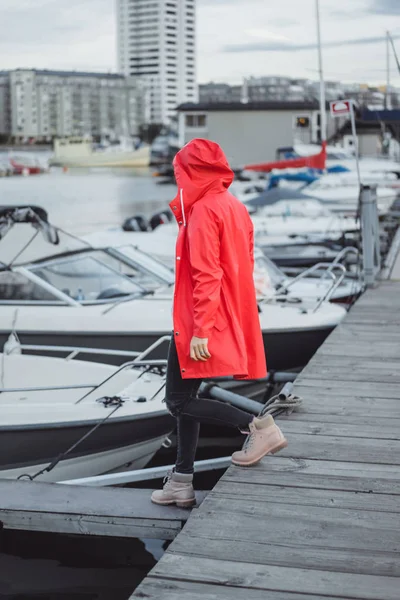 Beautiful young woman in a red cloak in the yacht port. Stockholm, Sweden