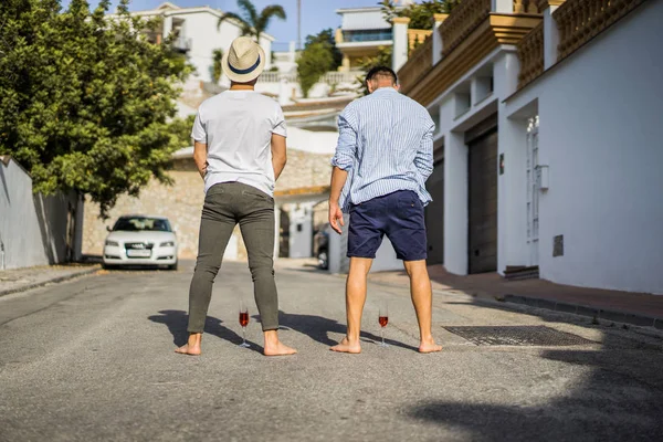 İki arkadaş, tropik yeşilliğin arka planında şampanya kadehleri olan genç adamlar.