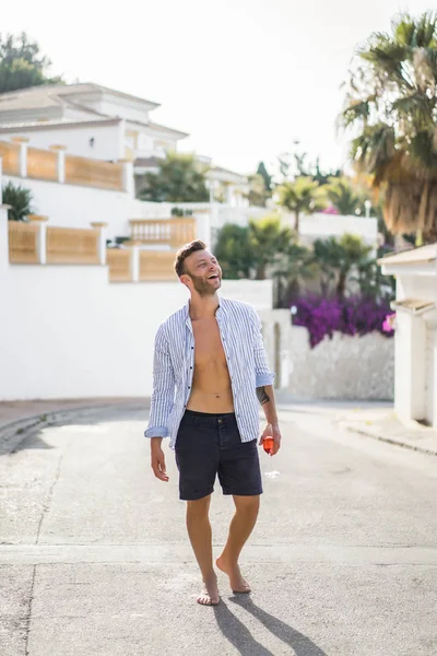 çizgili gömlekli, hasır şapka giyen bir adam, küçük bir İspanyol kasabasının sokaklarında yürüyor..