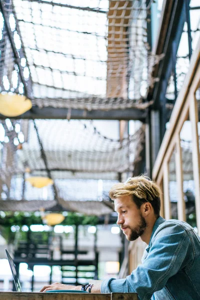 genç çekici iş adamı için bir dizüstü bilgisayar, bir kafe eserlerinde kahve içiyor.