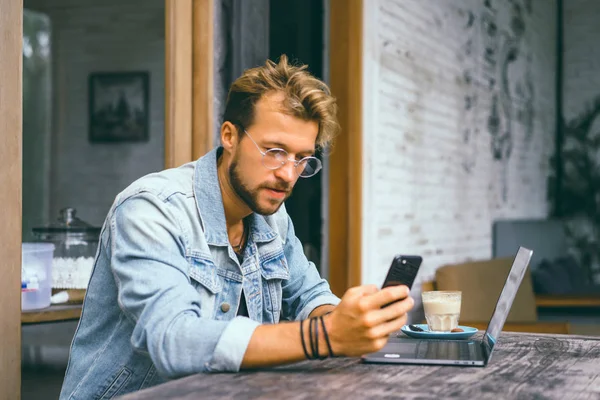 genç çekici iş adamı için bir dizüstü bilgisayar, bir kafe eserlerinde kahve içiyor.