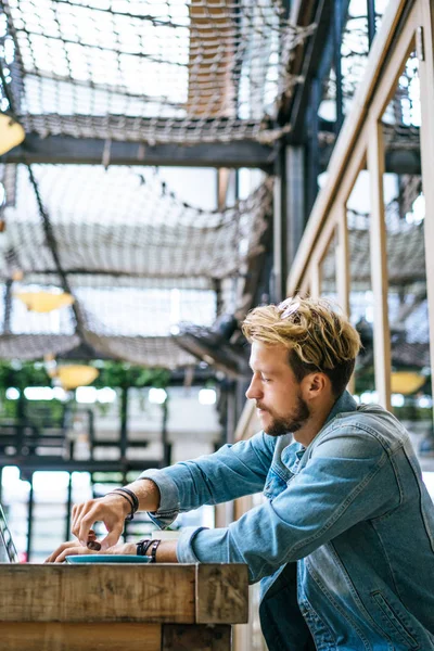 genç çekici iş adamı için bir dizüstü bilgisayar, bir kafe eserlerinde kahve içiyor.