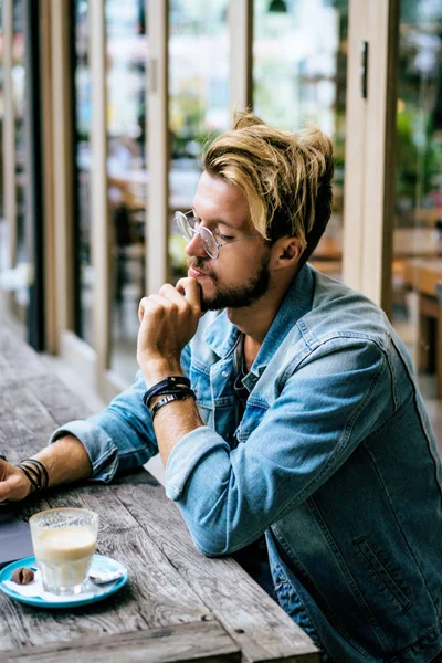 genç çekici iş adamı için bir dizüstü bilgisayar, bir kafe eserlerinde kahve içiyor.