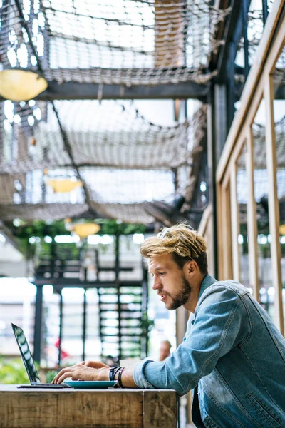 genç çekici iş adamı için bir dizüstü bilgisayar, bir kafe eserlerinde kahve içiyor.