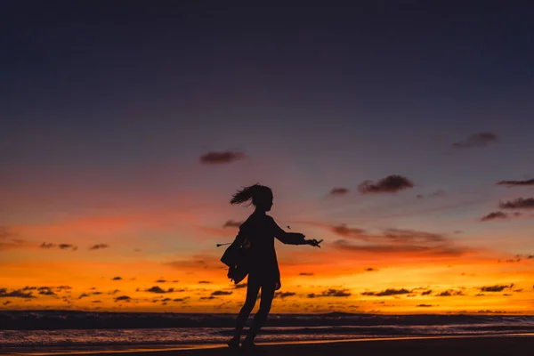 夕暮れ時のビーチの人々 夕日の背景に女の子をジャンプします — ストック写真