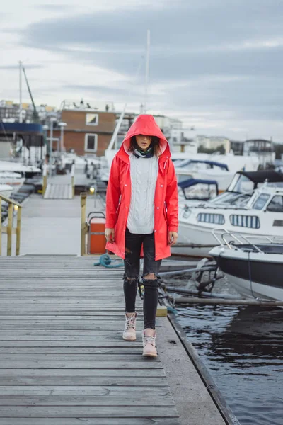 Beautiful young woman in a red cloak in the yacht port. Stockholm, Sweden