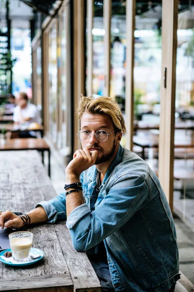 genç çekici iş adamı için bir dizüstü bilgisayar, bir kafe eserlerinde kahve içiyor.