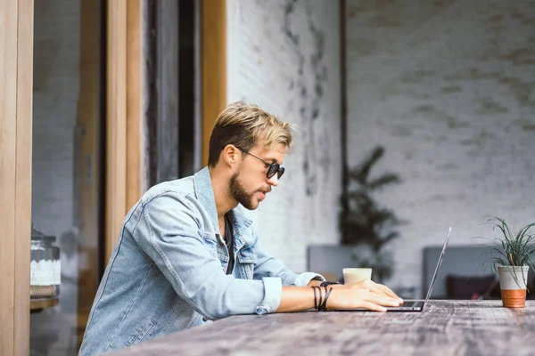 genç çekici iş adamı için bir dizüstü bilgisayar, bir kafe eserlerinde kahve içiyor.