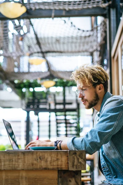 genç çekici iş adamı için bir dizüstü bilgisayar, bir kafe eserlerinde kahve içiyor.