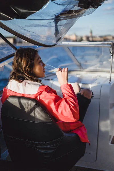 beautiful young woman in a red cloak drinking champagne on a yacht.