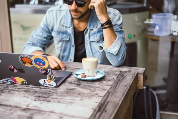 genç çekici iş adamı için bir dizüstü bilgisayar, bir kafe eserlerinde kahve içiyor.