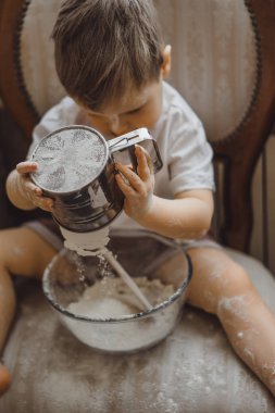 Mutfakta küçük çocuk anne pişirmek için yardımcı olur. Çocuk pişirme ilgilenmektedir.