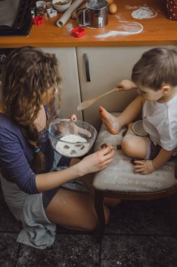 Mutfakta küçük çocuk anne pişirmek için yardımcı olur. Çocuk pişirme ilgilenmektedir.