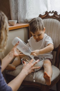 Mutfakta küçük çocuk anne pişirmek için yardımcı olur. Çocuk pişirme ilgilenmektedir.