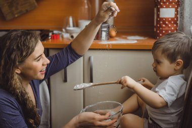 Mutfakta küçük çocuk anne pişirmek için yardımcı olur. Çocuk pişirme ilgilenmektedir.