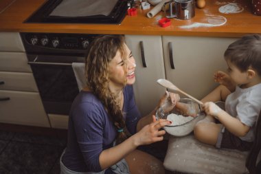 Mutfakta küçük çocuk anne pişirmek için yardımcı olur. Çocuk pişirme ilgilenmektedir.