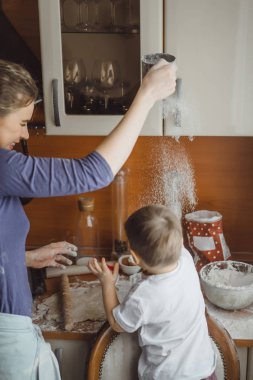 Mutfakta küçük çocuk anne pişirmek için yardımcı olur. Çocuk pişirme ilgilenmektedir.